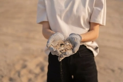 Image woman holding plastic in hands at beach