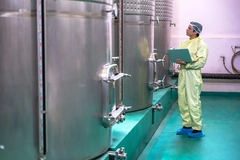 Image man standing next to fermentation tank