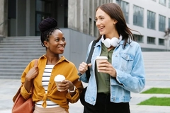 two women walking with coffee cups