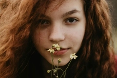 Image A girl with a flower over her mouth.