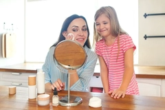 Image A mother taking her makeup off with her kid next to her.