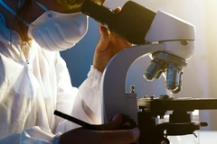 Image A scientist looking into a microscope in a lab setting