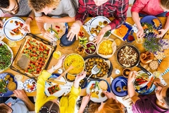 Image People at a table with lots of colorful foods.