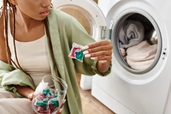 Women putting a laundry detergent pod into the laundry machine