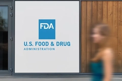 A woman blurry walking past a sign that says US Food and Drug Admiration.