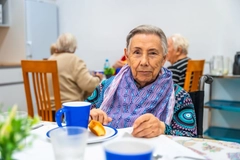 Image old woman with disability eating breakfast at nursing home