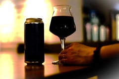 Image Glass of red wine next to aluminum can.