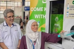 Image A person and person standing next to a machine.