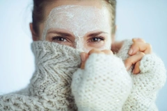 Image A woman with a facemask on covering half we face with her sweater.
