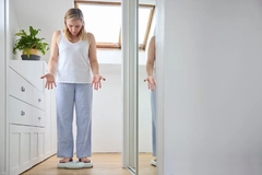 Woman on a scale having gained weight