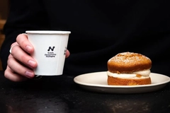 Image A hand holding a cup of coffee and a pastry