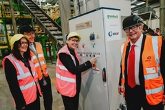 Image A group of people wearing safety vests and standing next to a machine