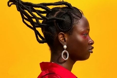 African woman with traditional hair style against yellow backdrop