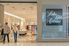 Image Two people walking into a Saks Fifth Avenue store.