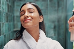 Woman spraying a face mist.