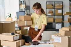 A person holding a box and a computer.