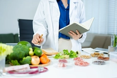 Image Female nutritionist in lab coat analyzing food and writing in notebook.