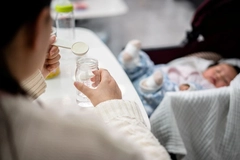 Image Woman making infant formula bottle