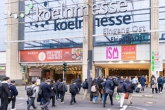 A group of people walking in front of a building for trade show