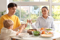 Image Little boy and his parents with glasses of water eating at table in kitchen