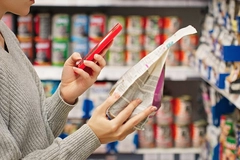 Image woman's hand scanning food package with smartphone inside supermarket