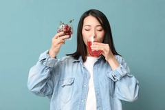 Image Woman drinking cherry flavored beverage.
