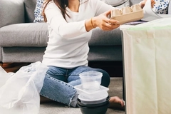 Image A person sitting on the floor with a tray of food