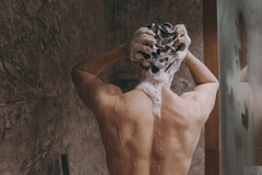 Image Man washing hair in shower, back to camera
