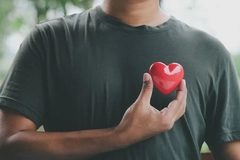 Image young man holding heart symbol in front of his heart