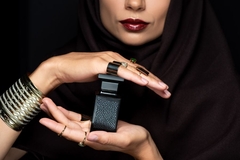 Image Woman in hijab holding fragrance bottle.