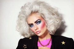 A woman with 80s style hair and colorful makeup.