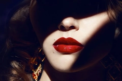 Image Woman applying red lipstick in shadows