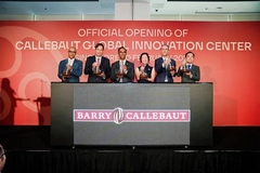Image five men and a woman on stage with red background holding brown liquid in flasks