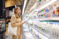 Image Young woman shops for dairy products in the grocery store.