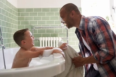 Image A father and son playing with bubbles in the bath.