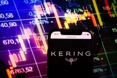 Image A phone with Kering on it and financials ups and downs in the background.