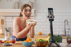 Image Asian fitness influencer live streaming showing healthy yogurt bowl in kitchen