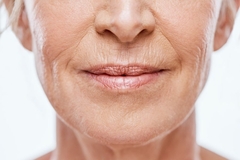 Image close up of an older womans lips, she is smiling.