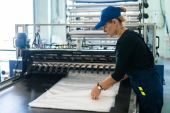 A person in a blue hat working on a sheet of plastic