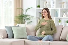 Image woman on couch touching stomach and chest smiling