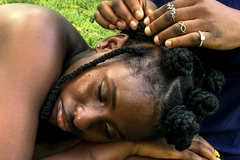 Image A woman lying down and getting her hair braided.