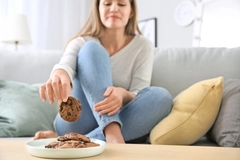 Image Woman eating chocolate cookies.