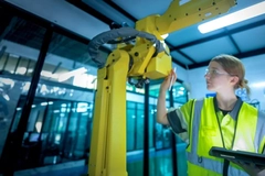 Image A person in safety vest checking a robot