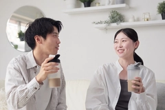 Asian man and woman in white shirts holding protein shake bottles