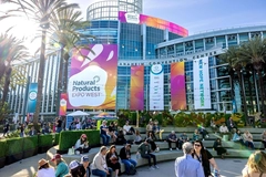 crowd of people outside building big building with natural products expo west banner and crowd of people outside