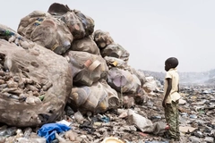 A child standing next to a pile of garbage