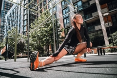 Image woman stretches outdoors in urban park wearing sportswear