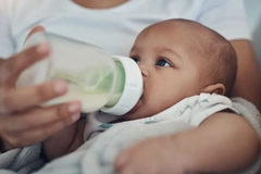 baby being bottlefed by mother