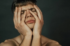 Image Stressed man holding face in hands