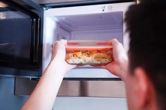 Image man putting glass tupper in microwave